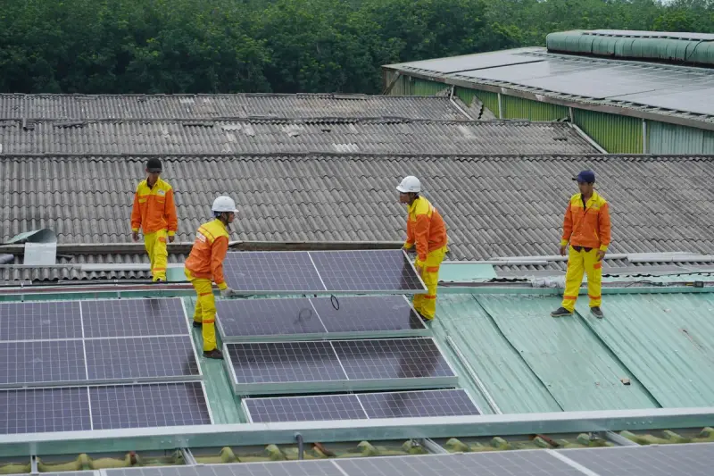 Workers installing solar panels on a roof
