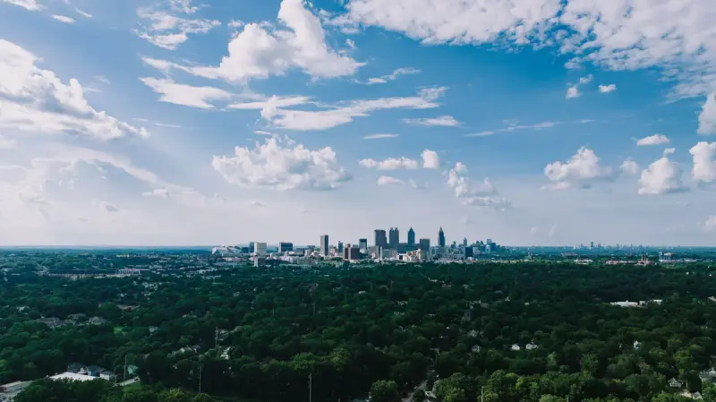 Aerial view of the Atlanta skyline surrounded by green trees under blue sky