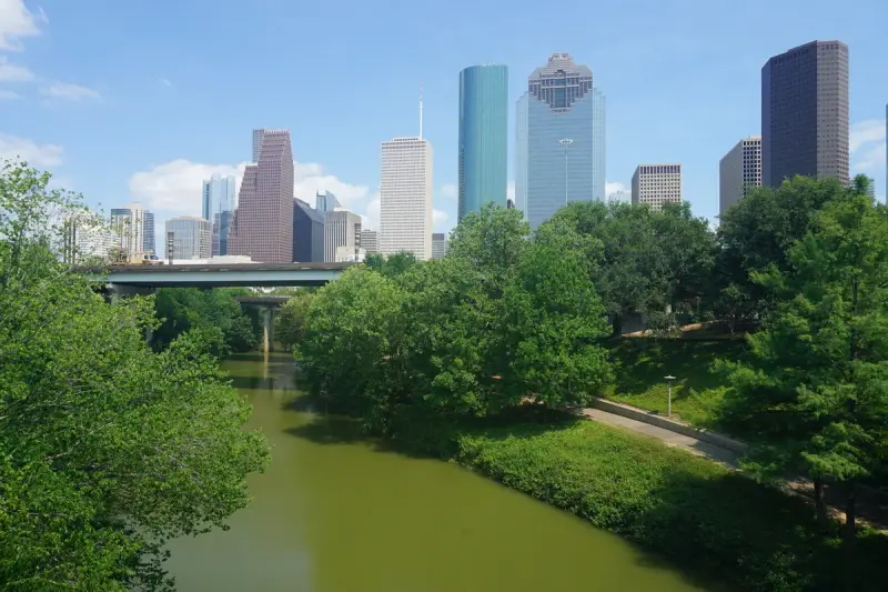 Buffalo Bayou Park winding through green trees toward the downtown Houston skyline