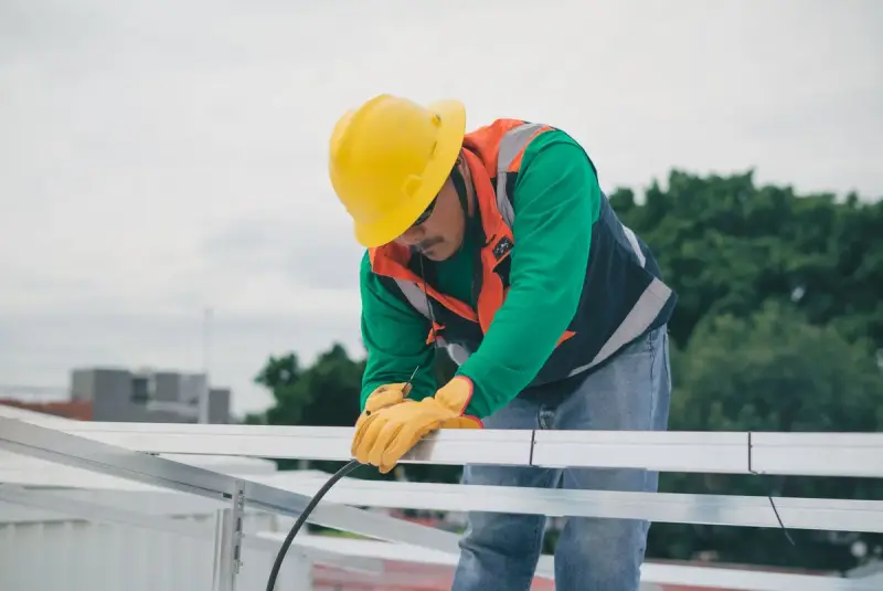 Worker in safety gear installing solar panels on a sunny day