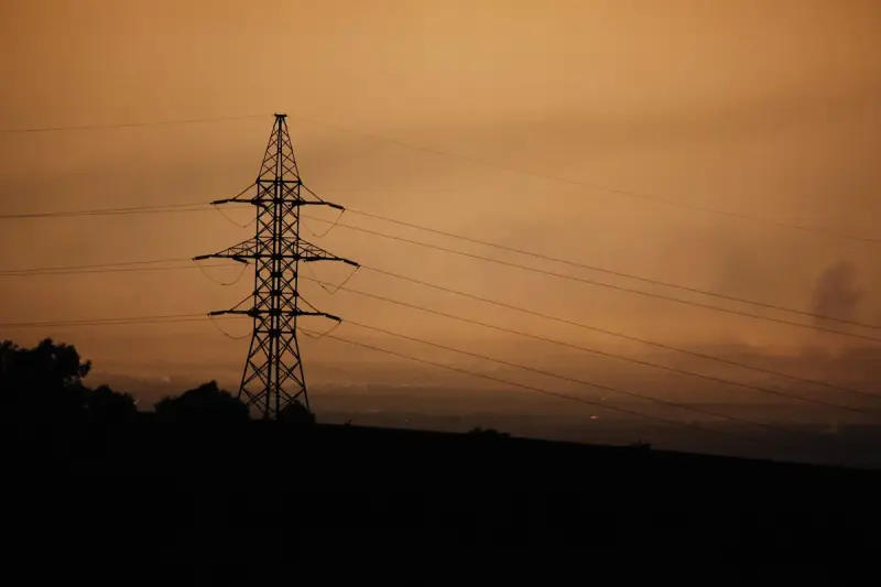 Power transmission tower silhouetted against a warm sunset sky