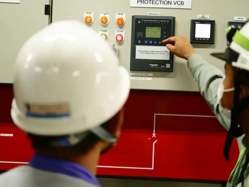 Engineers in safety gear operating an industrial control panel