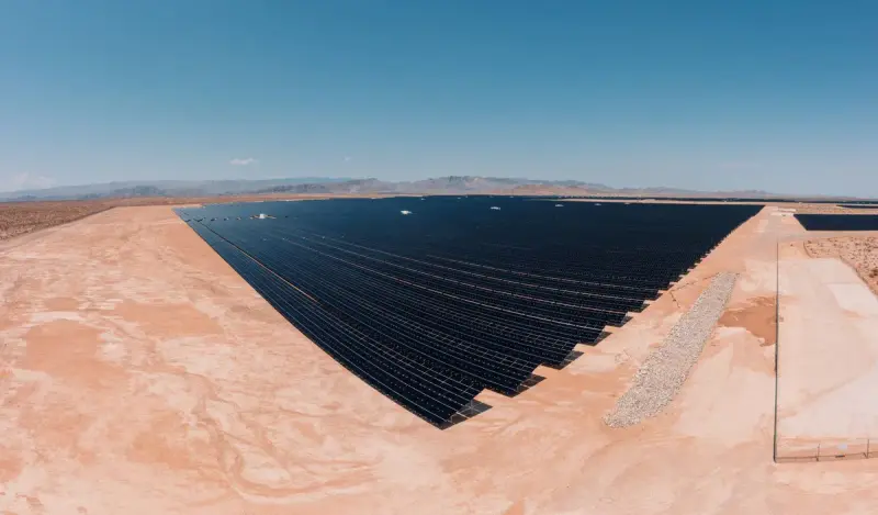 Aerial view of a large solar farm laid out across sandy desert ground