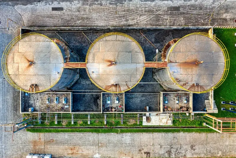 Top-down view of three round steel tanks with walkways and pumps