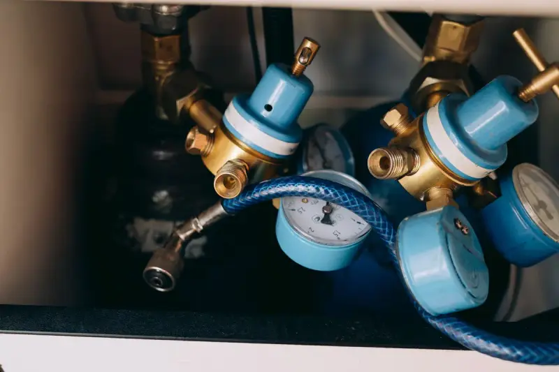 Blue and brass gas pressure regulators with gauges and a blue hose