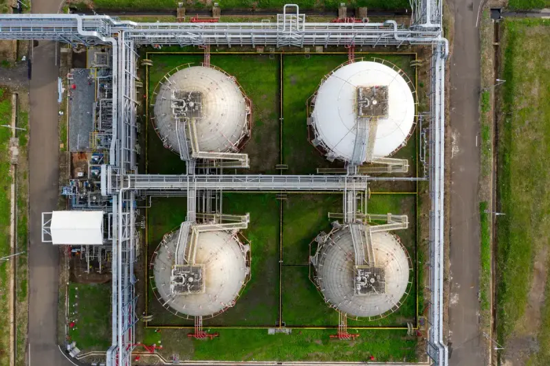 Aerial view of four spherical gas storage tanks linked by pipe racks
