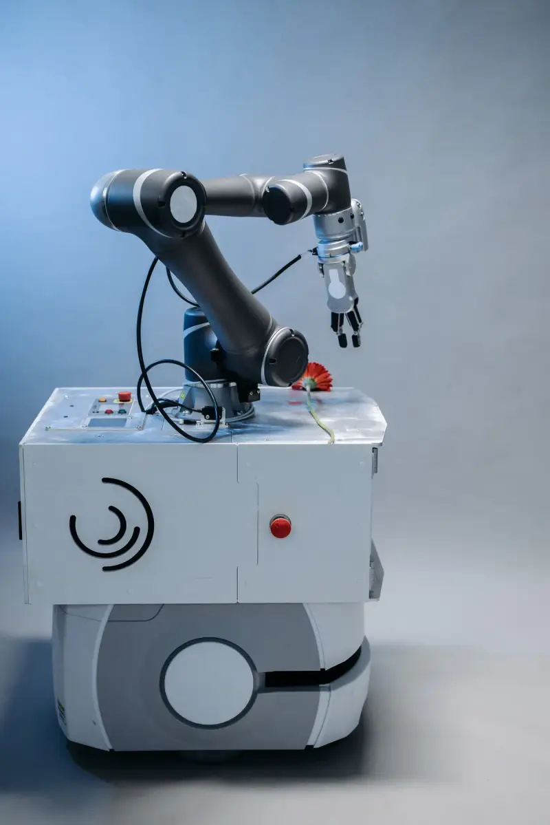 Robot arm with a two-finger gripper mounted on a white mobile base against a blue backdrop