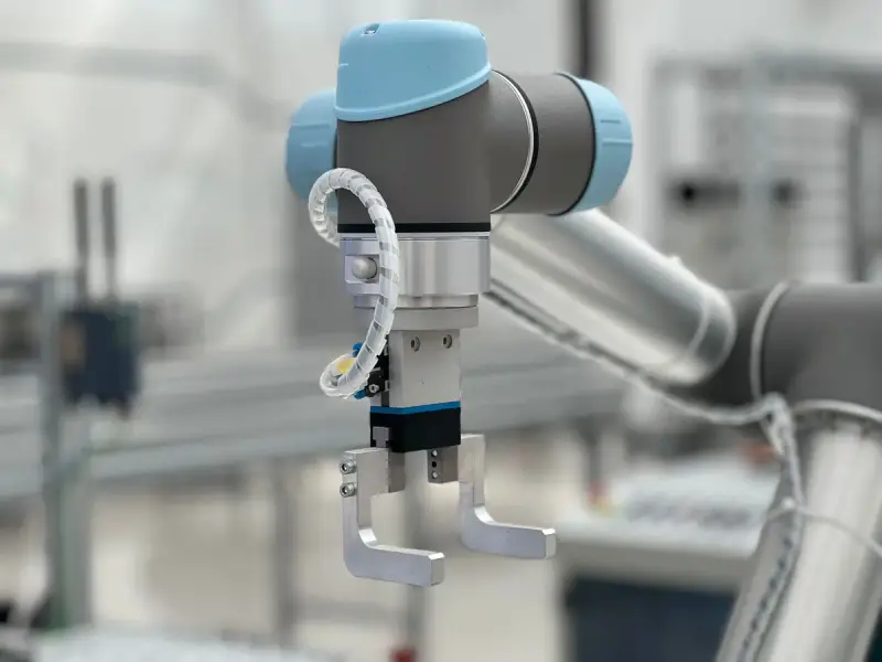 Collaborative robot wrist fitted with a parallel gripper and cable guide in a factory