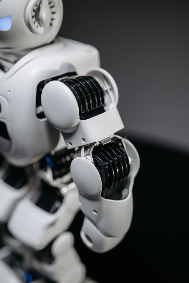 Close view of a white humanoid robot's shoulder and elbow joints with exposed gearing