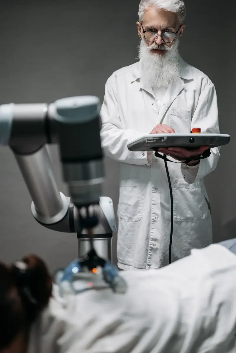 Engineer in a white coat programming a collaborative robot arm with a teach pendant