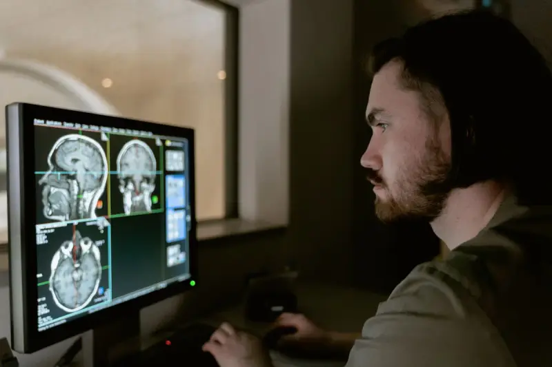 Imaging professional reviewing brain MRI slices on a monitor in a control room