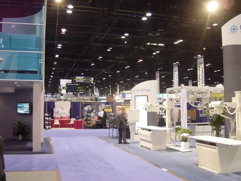 Carpeted aisle of the RSNA exhibit floor with X-ray equipment and numbered aisle banners
