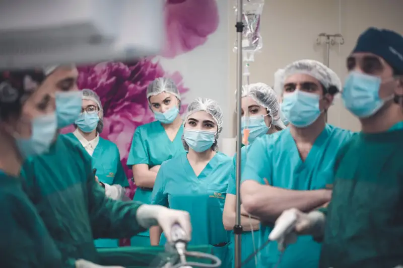 Surgical team at the table during a laparoscopic procedure with monitors overhead