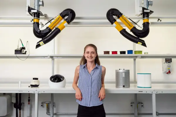 A woman standing beside equipment in an engineering laboratory.