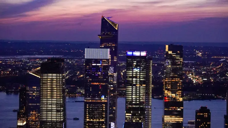 Midtown Manhattan towers lit at dusk under a purple sky