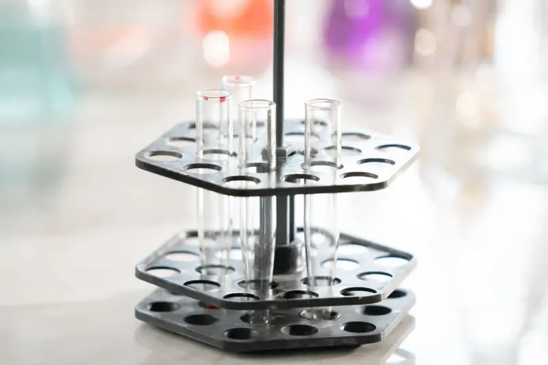 Empty glass test tubes in a tiered round rack on a bright lab counter
