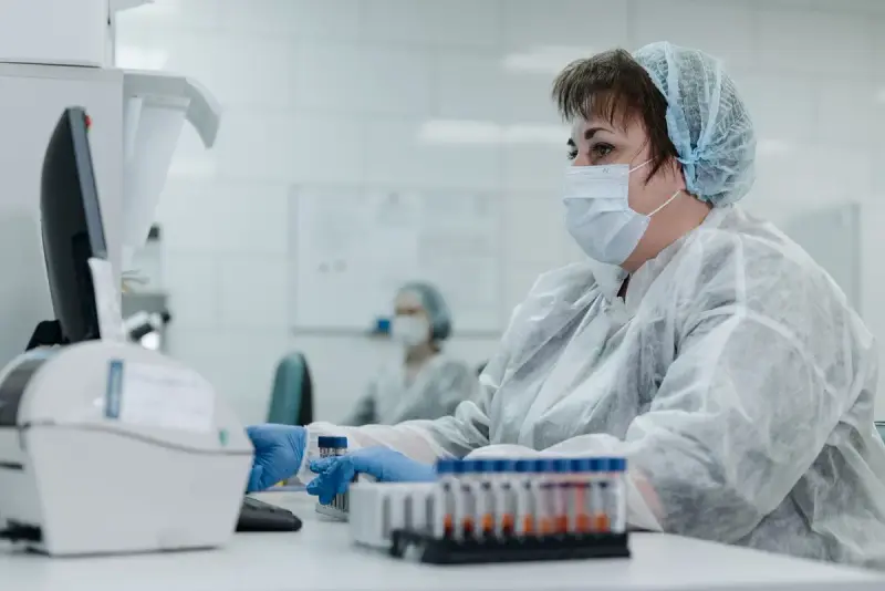 Lab scientist in protective gear working with samples and a monitor