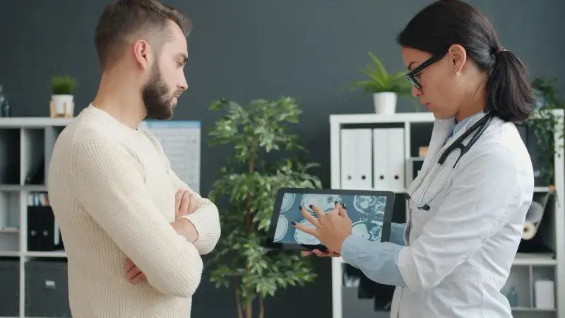 Doctor showing scan results on a tablet to a seated participant