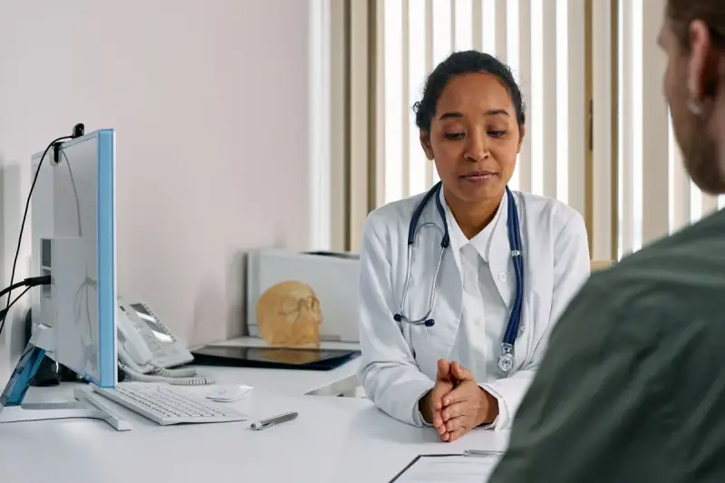 Clinician with a stethoscope talking with a participant in a modern office