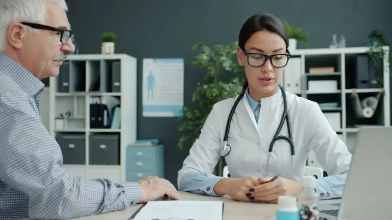 Medical professional talking with an older man in a modern office