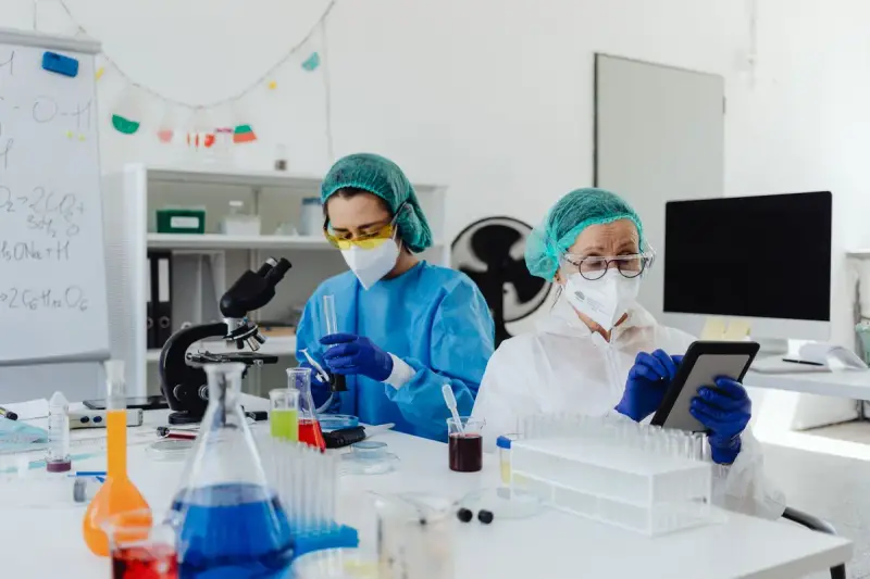 Researchers in a laboratory working with microscopes and digital tablets