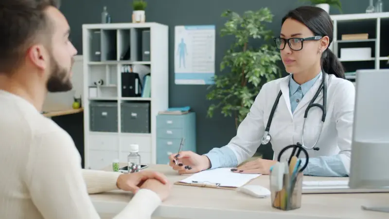 Doctor and participant talking across a desk in a modern clinic office