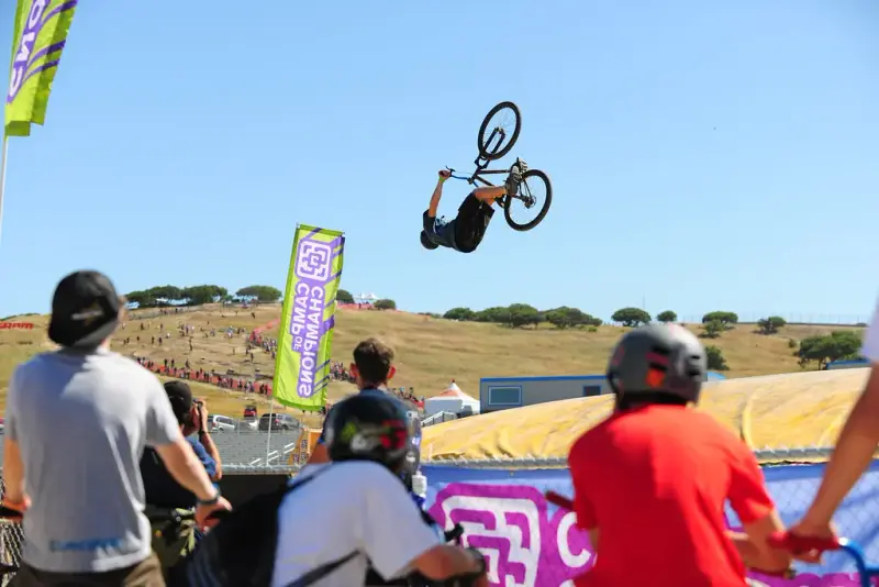 Spectators watching a rider flip a bike high above the dirt jumps at Sea Otter