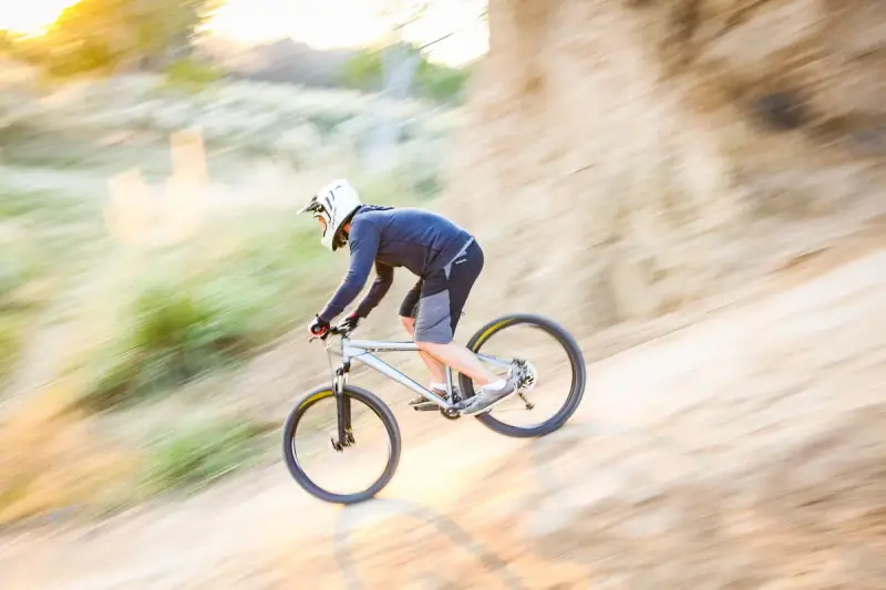 Mountain biker in a full-face helmet speeding down a dusty trail with motion blur