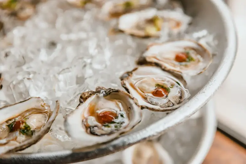 Freshly shucked oysters on the half shell resting on a tray of crushed ice