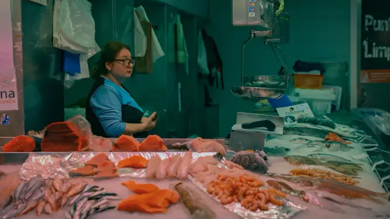 Woman behind a seafood counter displaying salmon, shrimp and whole fish on ice