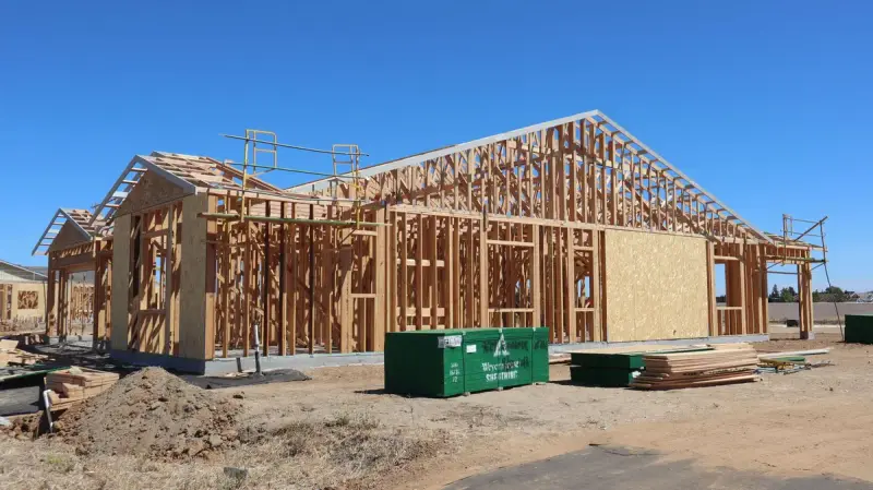 Wood frame of a new house under construction beneath a clear blue sky
