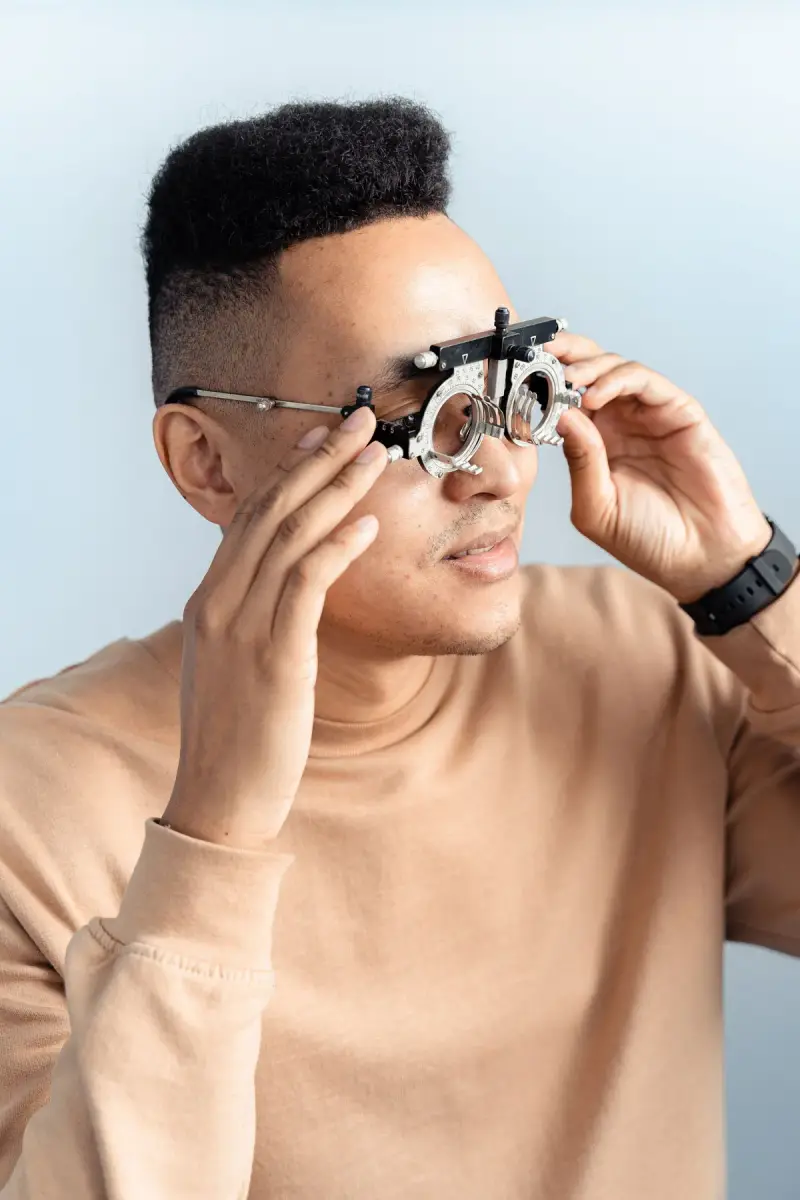 Man adjusting a trial lens frame during a vision test in an optometry clinic