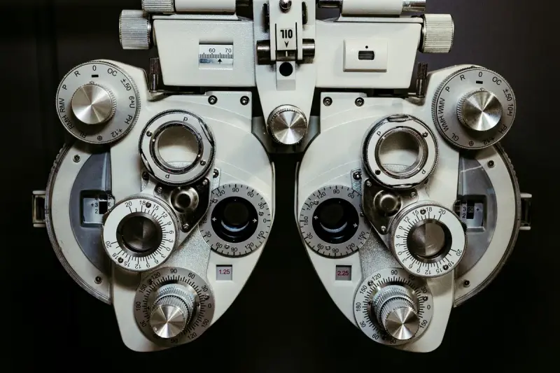 Front view of a phoropter with lens dials against a dark background