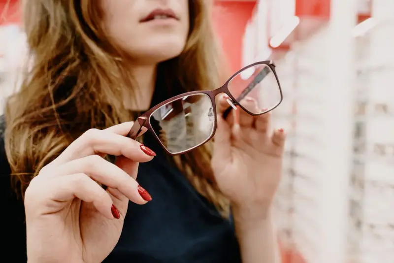 Woman examining modern eyeglass frames in an optical store