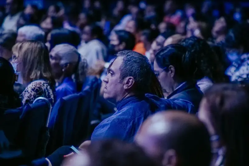 Large audience seated in rows listening closely during a talk in a big hall