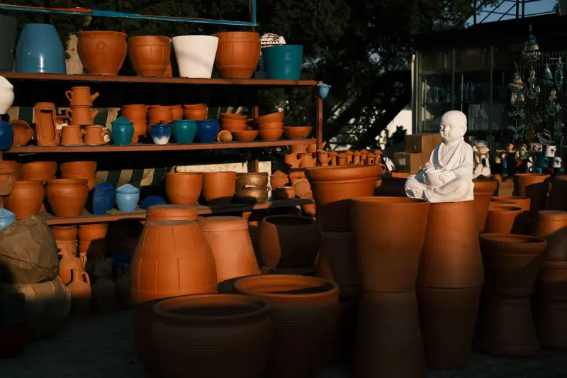 Clay pots and small sculptures on wooden shelves in warm light