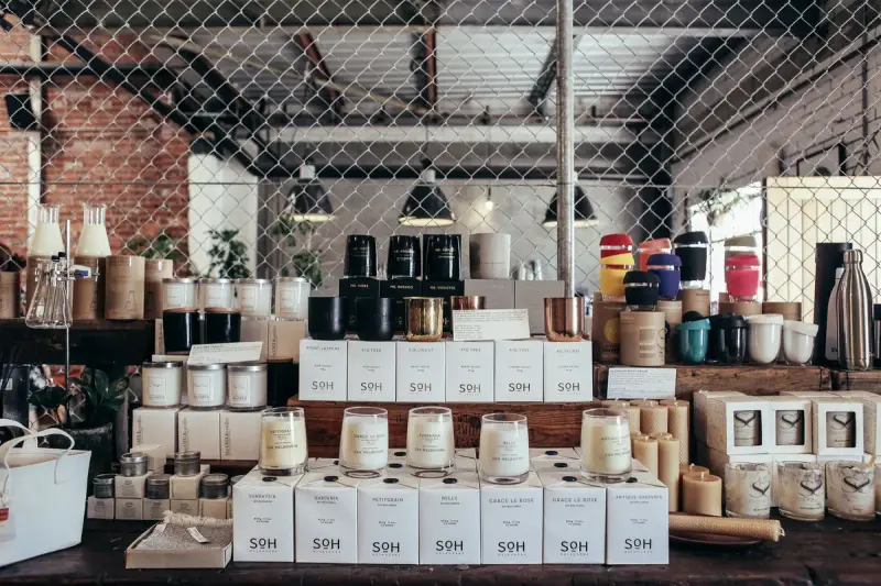 Handmade candles in boxes and home goods arranged on a rustic counter