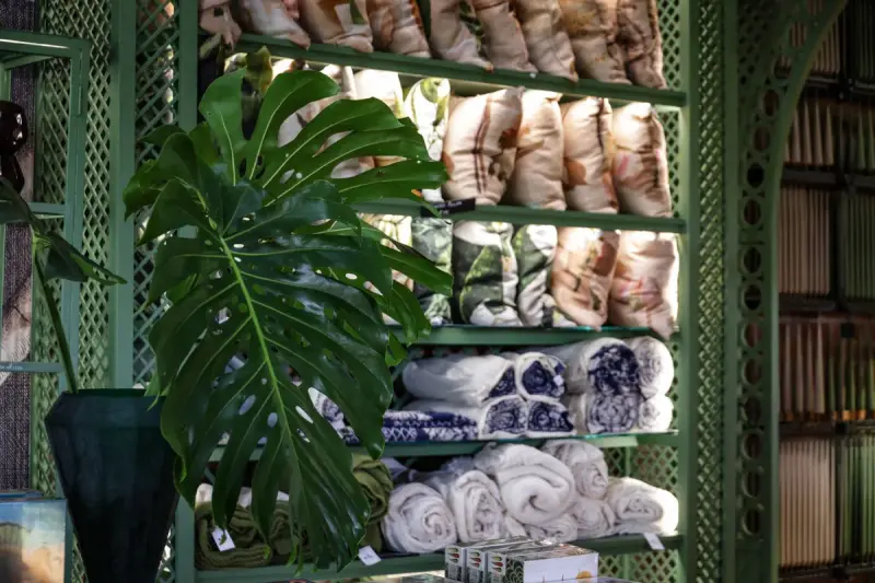 Store interior with green walls, monstera leaves and folded textiles on display