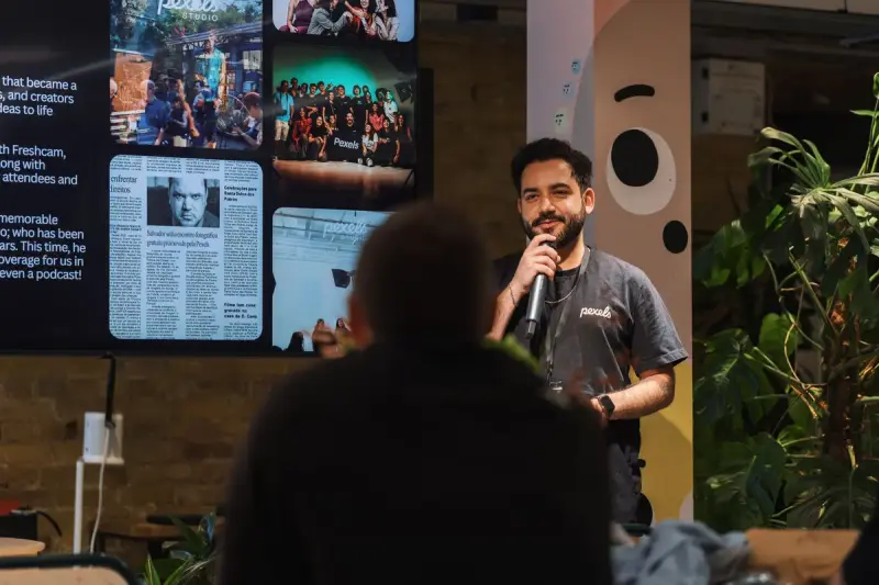 Speaker with a microphone addressing a seated audience at an indoor event