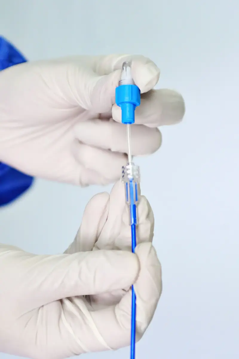 Gloved hands joining a blue catheter to its hub and introducer