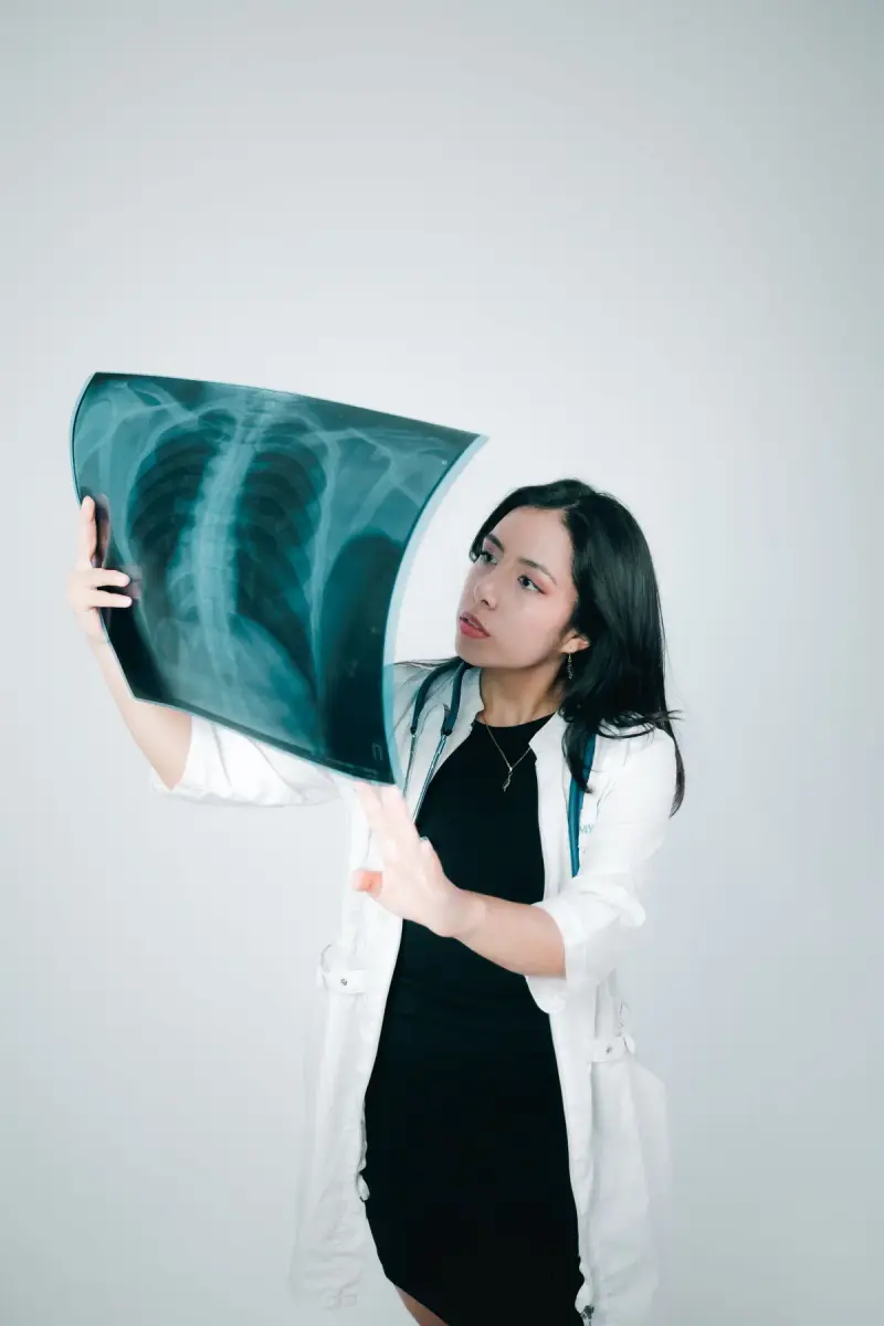 Young woman doctor in a white coat studying a chest X-ray against the light