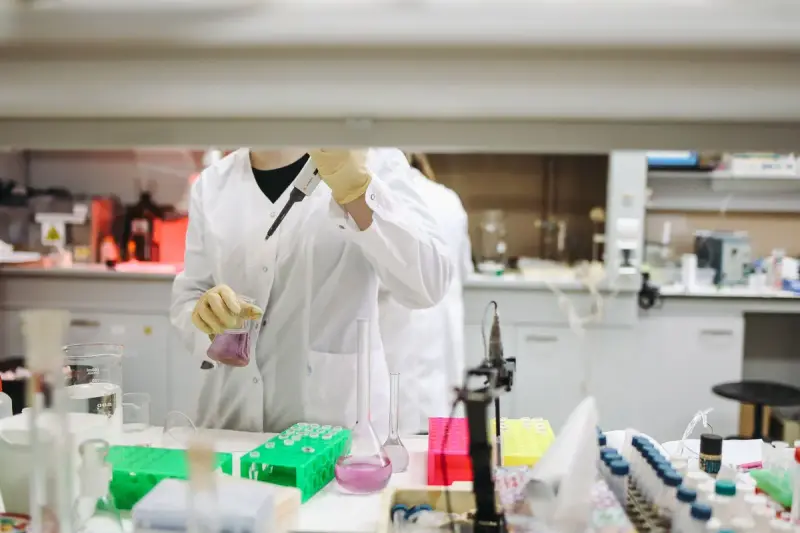 Scientist handling samples at a crowded lab bench lined with tubes and equipment
