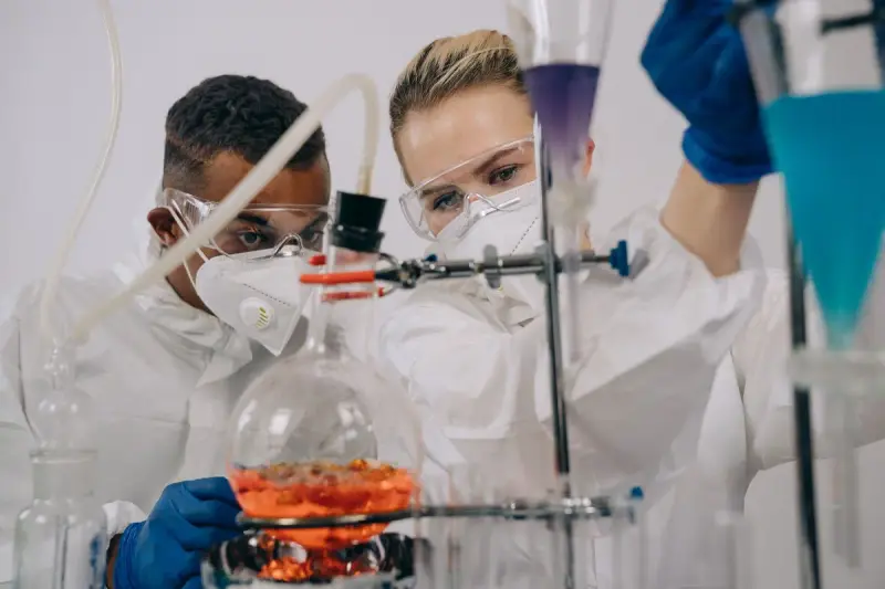 Two scientists in protective gear running an experiment together