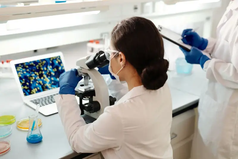 Woman scientist in a lab coat examining samples under a microscope