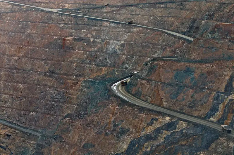 Aerial view of an open-pit mine with haul trucks on winding roads