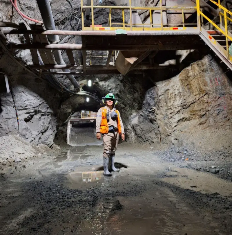 Engineer in safety gear standing in a lit underground mine tunnel