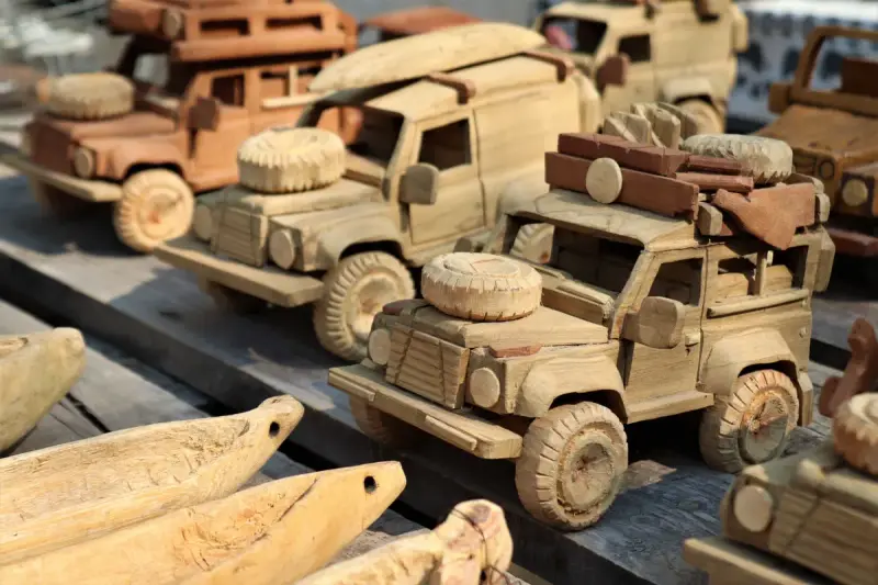 Hand-carved wooden toy trucks lined up on a market display