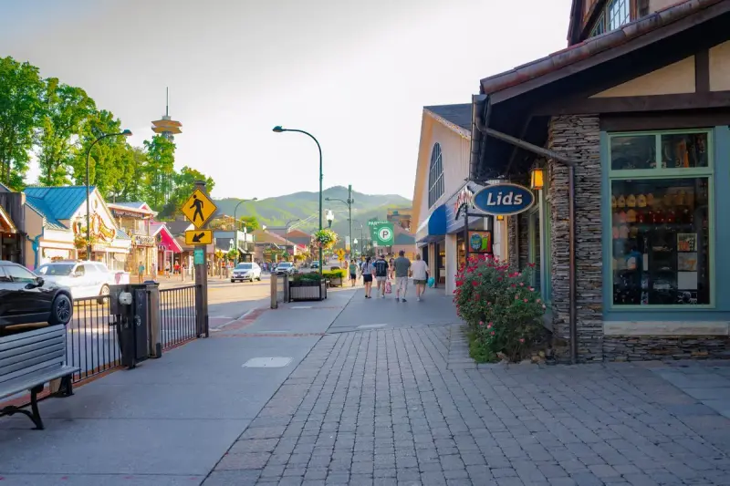 Gatlinburg street lined with shops and visitors walking, with mountains in the distance