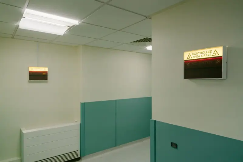 Hospital corridor with lit controlled-area radiation warning signs above the doorways