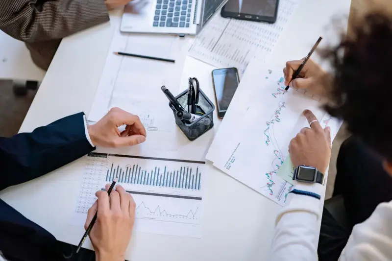 Top view of a team annotating charts and graphs on a shared table